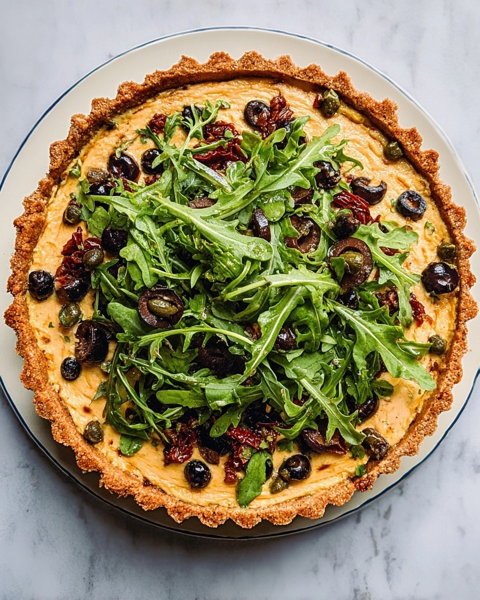 The image shows a round tart with a thick, golden-brown crust and an even light yellow filling as the first layer. On top of the filling is a layer of fresh green arugula leaves scattered all over, mixed with sliced black olives and small pieces of dark red sun-dried tomatoes. There are also a few small brown capers spread across the arugula layer. The tart sits on a white plate placed on a white marbled surface, with soft natural light highlighting the textures and colors of the ingredients. Photo taken with an iphone --ar 4:5 --v 7