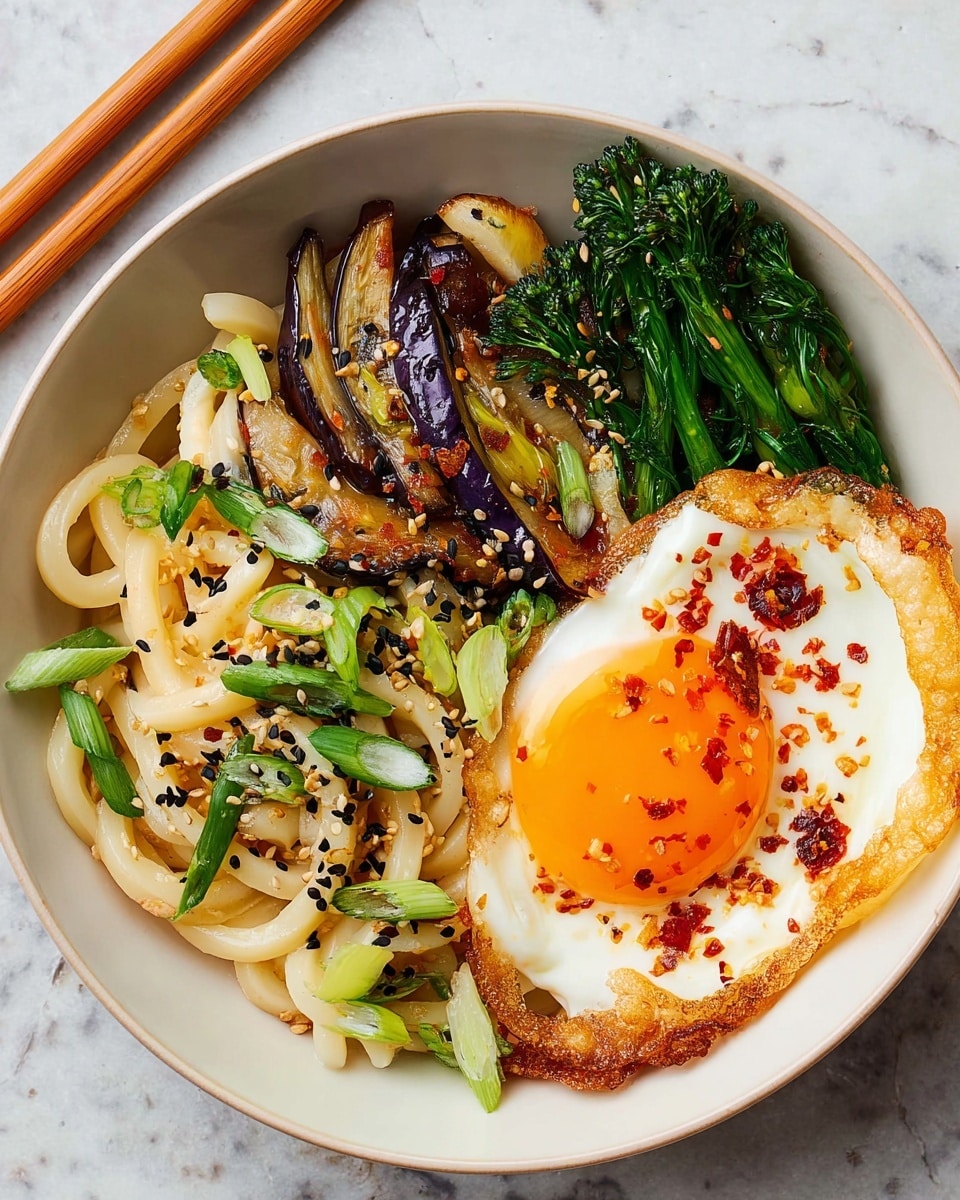 A white bowl holds a colorful dish with three main layers: on the bottom, thick, pale yellow udon noodles mixed with light green sliced scallions and dark green broccolini, scattered with small black sesame seeds; on top of the noodles, there are thin, round slices of light purple eggplant and caramel-colored sautéed onions; finally, a bright sunny-side-up egg with a rich orange yolk and crispy golden edges sits on the right side of the bowl, sprinkled with black sesame seeds and red chili flakes. The bowl is placed on a white marbled textured surface with wooden chopsticks resting at the top left edge. photo taken with an iphone --ar 4:5 --v 7