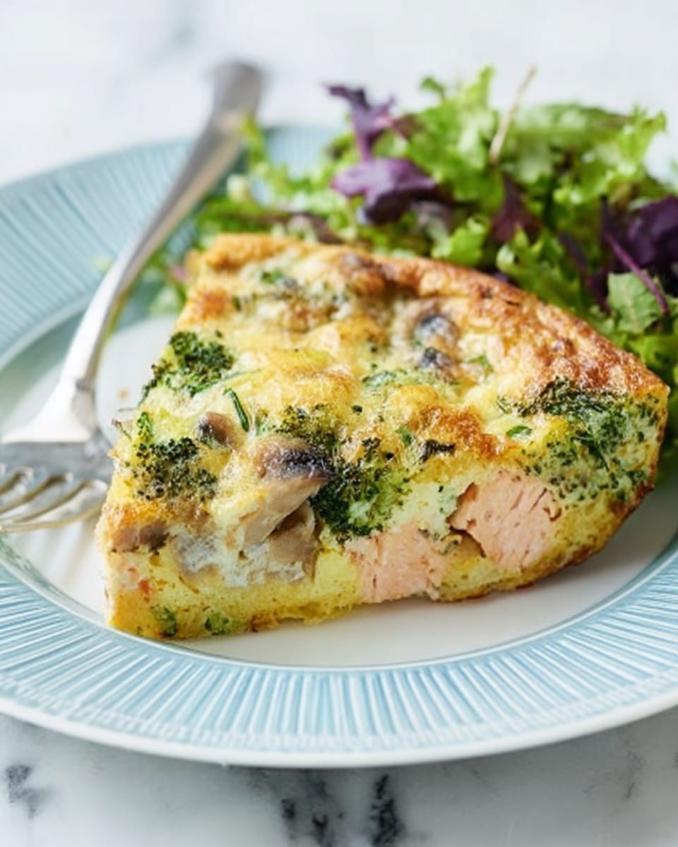 A slice of thick frittata sits on a white plate with light blue ridges, showing three visible layers: a pale yellow egg base at the bottom, a middle layer with light-pink pieces of salmon, and a top layer with bright green broccoli and mushrooms mixed with melted cheese. The frittata has a slightly browned, textured surface with herbs scattered throughout. Next to it, fresh green and purple salad leaves add color and a fresh look. A silver fork rests on the left side of the plate. The plate is set on a white marbled surface. photo taken with an iphone --ar 4:5 --v 7