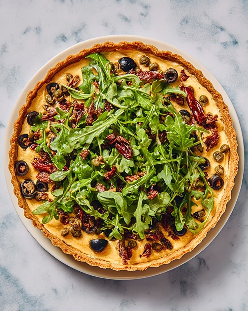 A round tart with a golden crust is topped with a creamy, light orange layer as the base. On top of this layer, there is a generous pile of fresh green arugula leaves spread unevenly, mixed with sliced black olives scattered across the greens. There are pieces of sun-dried tomatoes and small capers placed randomly on the arugula, adding pops of dark red and brown colors. The tart sits on a white plate, all placed on a white marbled surface. photo taken with an iphone --ar 4:5 --v 7