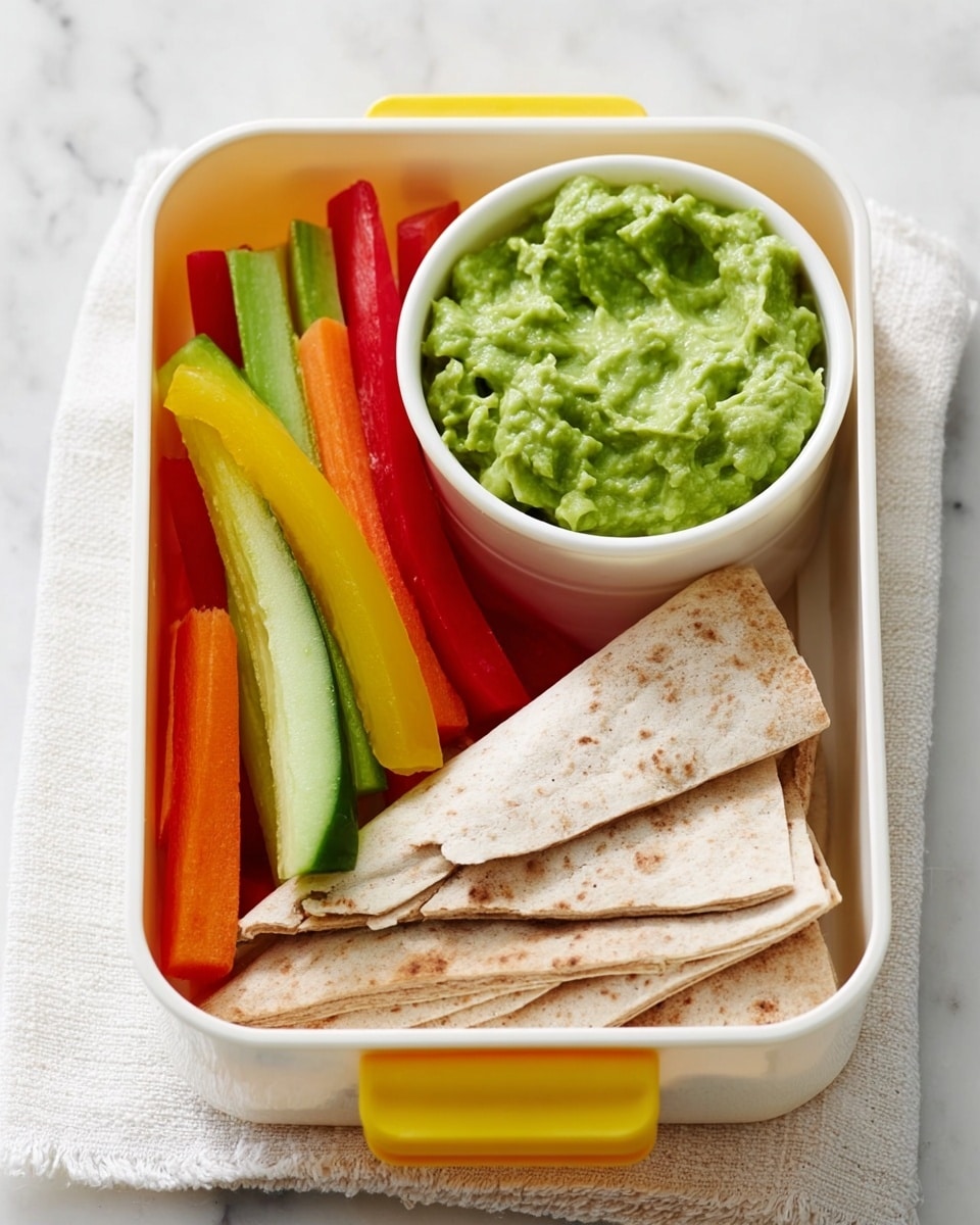 A white lunch box with a small white bowl inside filled with green guacamole, placed on the top right. Next to it, on the left side, are colorful vegetable sticks in yellow, green, orange, and red, arranged together. At the bottom right of the lunch box, there are pieces of folded flatbread that show a light brown color and soft texture. The whole lunch box is sitting on a white marbled surface with a white cloth underneath. photo taken with an iphone --ar 4:5 --v 7