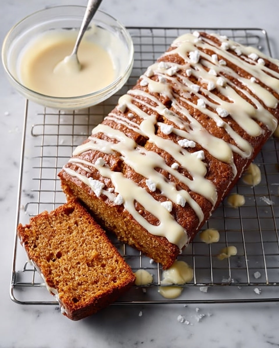 A square cake with a golden brown top sits on a cooling rack, with one square piece cut out and placed next to it. The cake has a soft, moist texture and is covered with a drizzle of creamy white icing in a zigzag pattern. Small white chunks are sprinkled over the icing, adding a crumbly texture. In the background, there is a clear glass bowl with more white icing and a spoon inside it, placed on a white marbled surface. Some icing drips are seen on the cooling rack and surface. Photo taken with an iphone --ar 4:5 --v 7