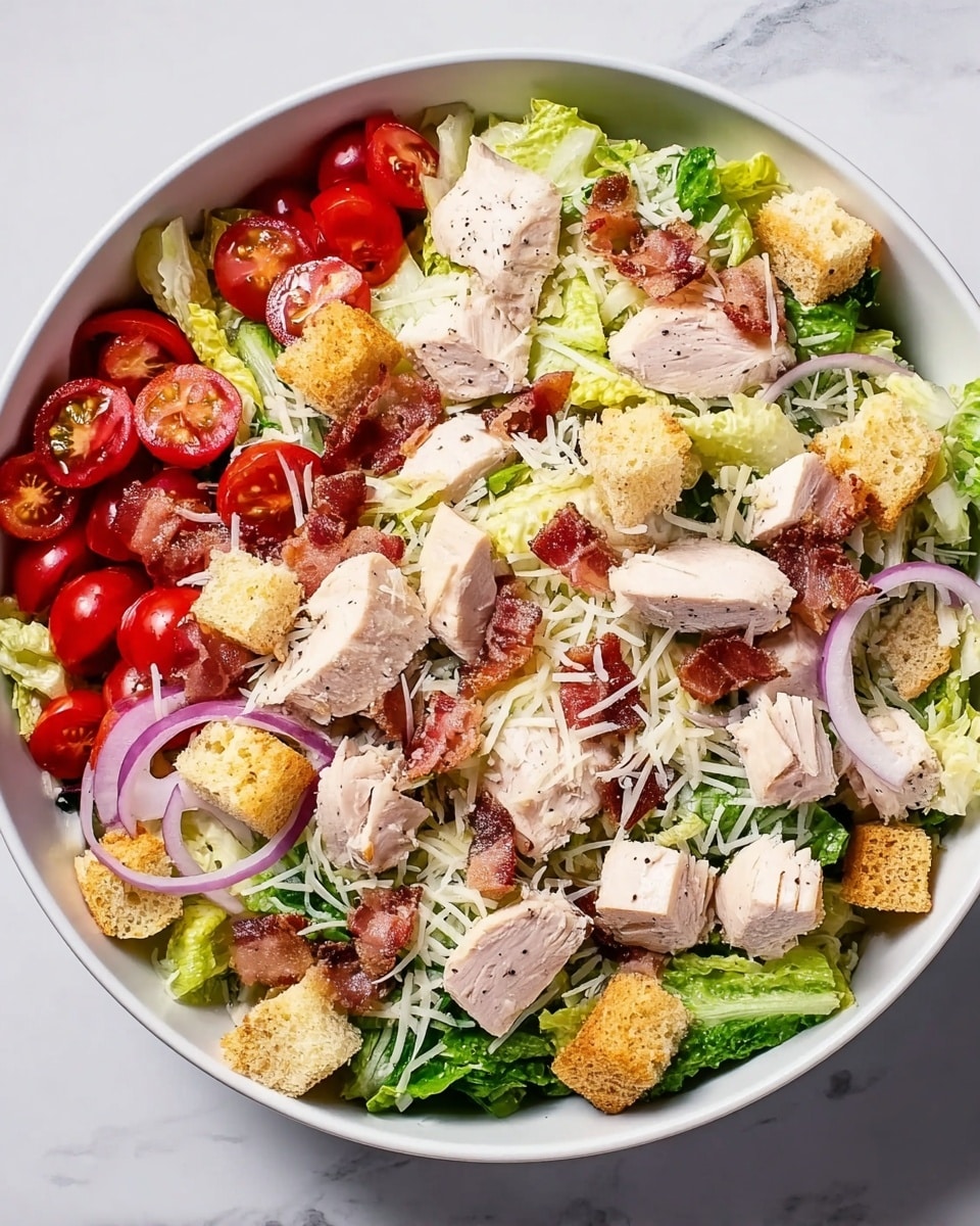 A white bowl filled with a fresh salad consisting of a base layer of green romaine lettuce. On top, there are chunks of white cooked chicken scattered throughout, along with halved red cherry tomatoes. Thin slices of light purple onion are spread across the bowl. Crispy golden-brown croutons are placed evenly over the salad. There are small pieces of pink bacon mixed in, and a light sprinkling of grated white cheese covers parts of the dish. All ingredients sit on a white marbled surface with a glass of yellow liquid visible in the top right corner. Photo taken with an iphone --ar 4:5 --v 7