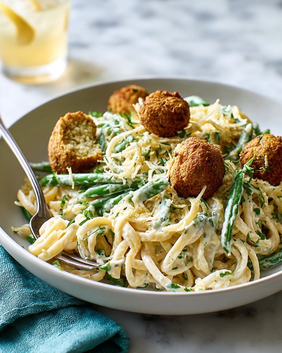 A white bowl filled with creamy white pasta noodles mixed with green beans and sprinkled with chopped green herbs, topped with four golden-brown crispy balls, one broken open showing a soft inside; a silver fork rests inside the bowl on the left side, the bowl placed on a white marbled surface with a teal cloth near the bottom right corner. Photo taken with an iphone --ar 4:5 --v 7