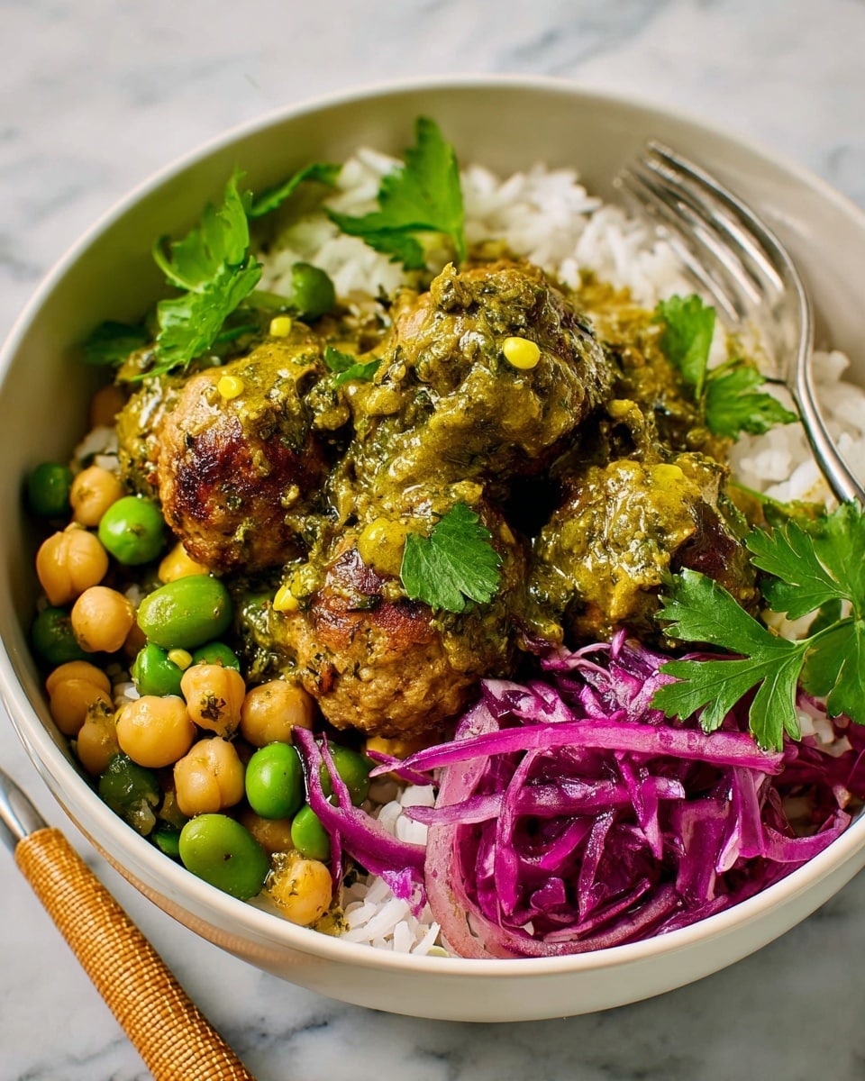 A white bowl filled with a dish that has four main layers: at the bottom is a bed of white rice with a few green herb leaves mixed in, above it are brown meatballs covered in a thick green sauce with visible herbs and small red bits, scattered around the meatballs are light yellow chickpeas, and on one side of the bowl is a portion of thinly sliced purple cabbage with some green herb leaves on top. The bowl sits on a white marbled surface with a wrapped silver utensil nearby. Photo taken with an iphone --ar 4:5 --v 7